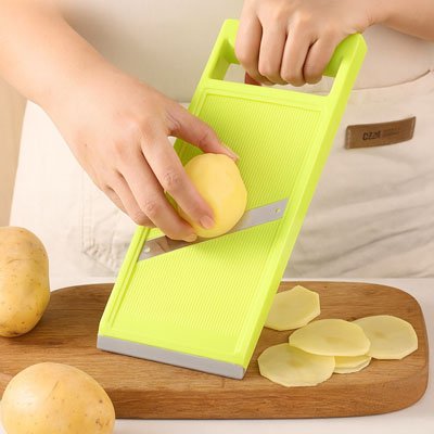 Mandoline de cuisine réglable, coupant un légume en tranches fines et uniformes.