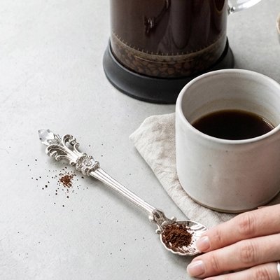 Cuillère à café en métal alignée sur une table de cuisine blanche