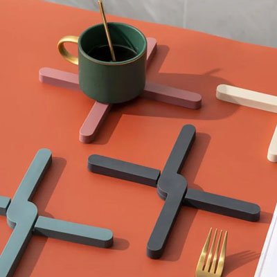 Dessous de plat rose en croix supportant une tasse verte avec cuillère dorée