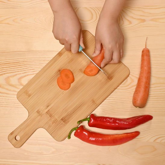 planche de découpe utilisé pour trancher des carottes et des piments rouges