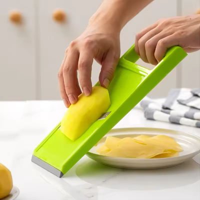 Mandoline de cuisine avec poussoir noir, éminçant un légume au‑dessus d’un bol.