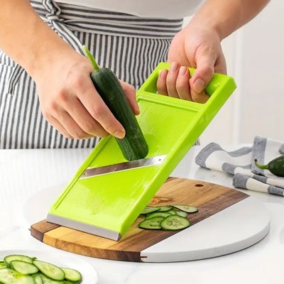 Mandoline de cuisine en action, produisant des bandes régulières de légume.