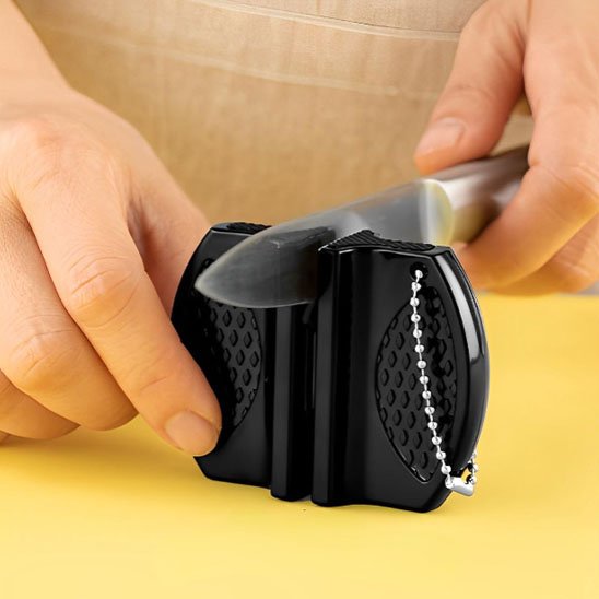 Affûteur de couteau  professionnel maintenant la lame pendant l’aiguisage en cuisine.
