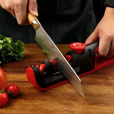 Aiguiseur de couteau manuel utilisé pour affûter une lame de cuisine sur un plan de travail.