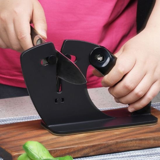 Aiguiseur de couteau moderne employé pour affûter une lame de cuisine sur une planche en bois.