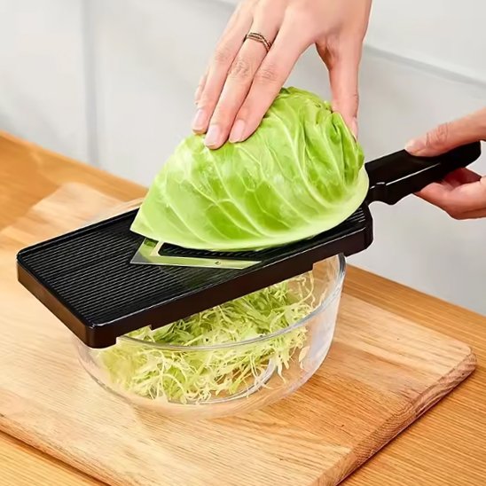 Coupe‑légume compact utilisé pour râper du chou dans un bol en verre.