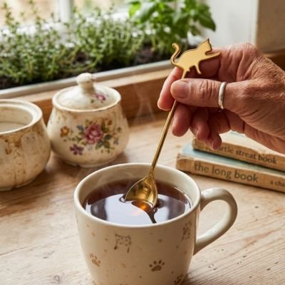 Cuillère à café décorative tenant du sucre au‑dessus d’un bol en céramique.