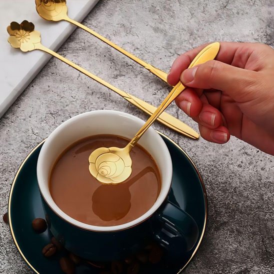 Cuillère à café dorée avec motif floral, utilisée pour remuer le café