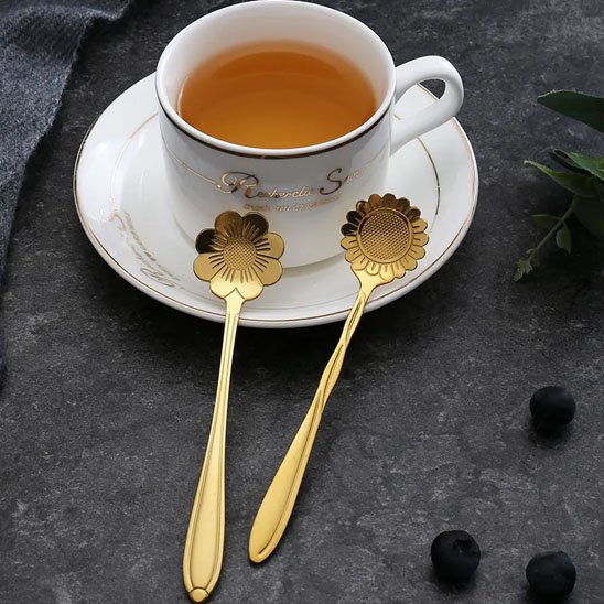 Cuillère à café dorée plongée dans une tasse de café.