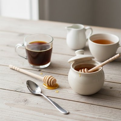 Cuillère à miel en bois reposant dans un pot de miel sur une table en bois.