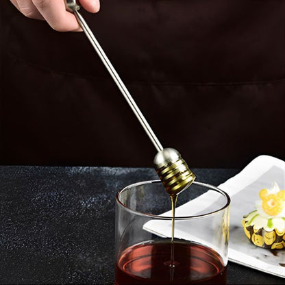 Cuillère à miel métallique utilisée pour sucrer une tasse de thé dans une ambiance chaleureuse.