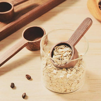 Cuillère doseuse en bois avec café moulu et grains autour.