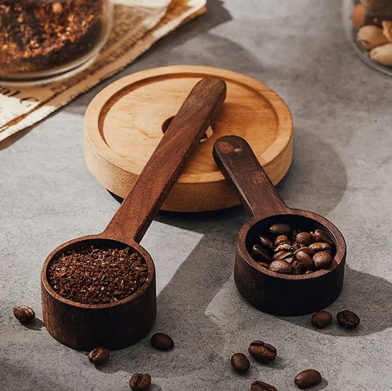 Cuillère doseuse en bois remplie de café moulu.