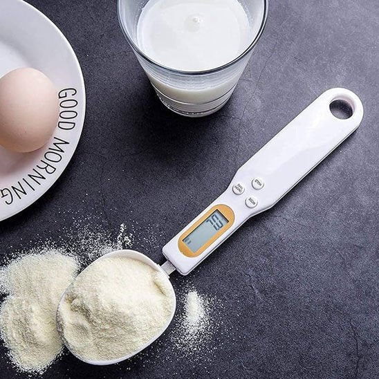 Cuillère doseuse numérique utilisée pour mesurer du lait en poudre blanche.