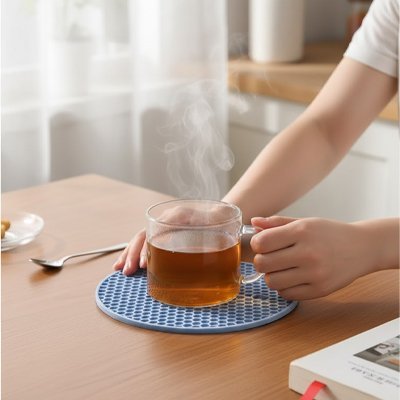 Dessous de plat antidérapant bleu supportant une tasse en verre remplie de café fumant.