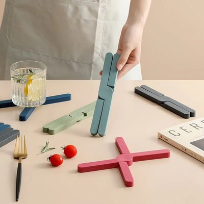 Dessous de plat de couleur vert et rouge  posé sur une table de cuisine moderne.