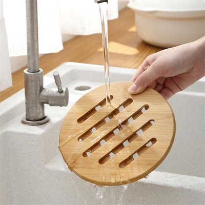 Dessous de plat en bois entrain d'être laver dans un évier avec de l'eau propre. 
