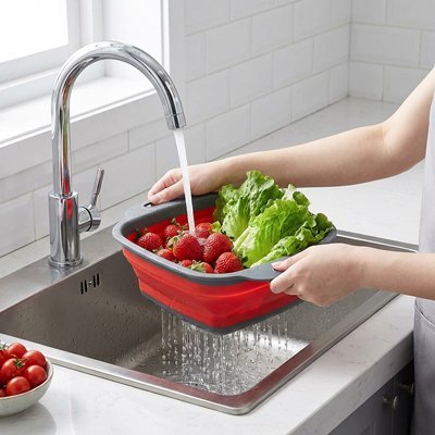 Femme rinçant des fruits dans une passoire pliable pratique en cuisine