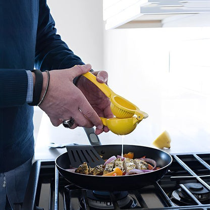 Main pressant un citron avec un presse‑agrume manuel dans une poêle dans une cuisine.
