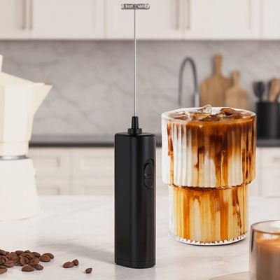 Main versant du lait tout en utilisant un mousseur à lait électrique.