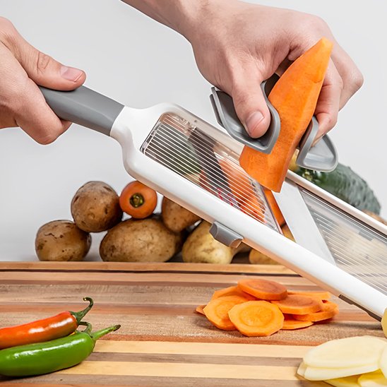 Mandoline blanche avec poussoir de sécurité tranchant un concombre.