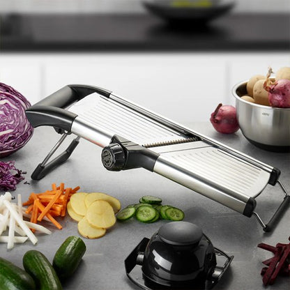 Mandoline japonaise avec poussoir noir, tranchant un légume sur le plan de travail.