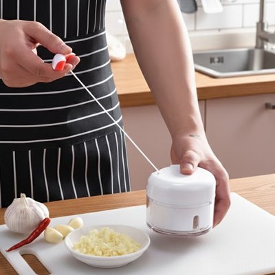 Mini hachoir manuel actionné pour préparer des légumes rapidement.