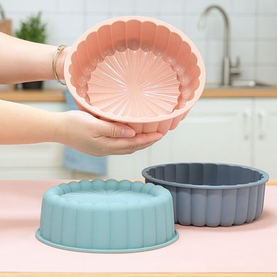 Moules à gâteau souples en silicone tenus en main dans une cuisine moderne.