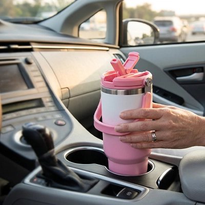 Mug isotherme de couleur rose pâle rangé dans une voiture lors d'un déplacement.
