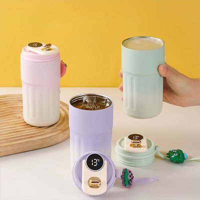 Mug isotherme rose et blanc avec couvercle à thermomètre posé sur une table.