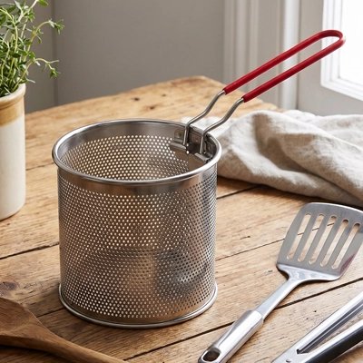 Passoire en acier inoxydable perforée, utilisée pour égoutter des aliments après cuisson.