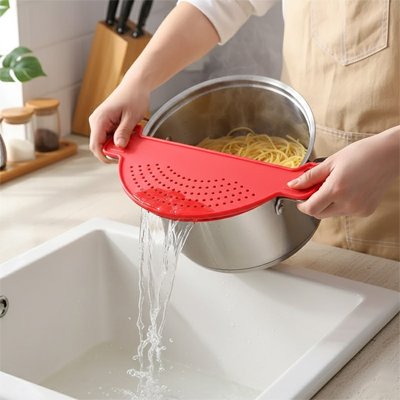 Passoire en silicone fixée sur une casserole pour égoutter des pâtes chaudes.