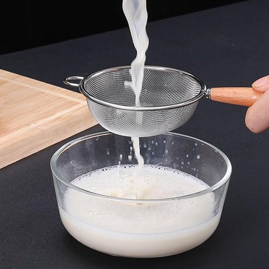 Passoire fine en métal utilisée pour filtrer un liquide dans un bol en verre.
