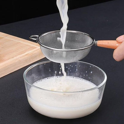 Passoire fine en métal utilisée pour filtrer un liquide dans un bol en verre.