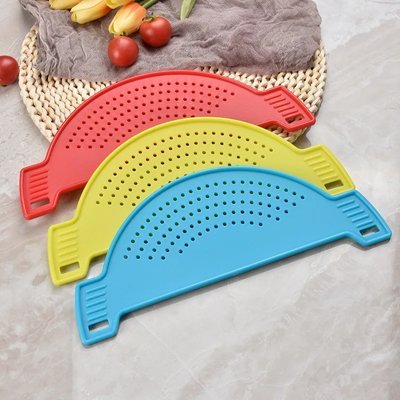 Passoire pratique en silicone de couleur bleu, rouge et jaune posé près des tomates sur un comptoir de cuisine