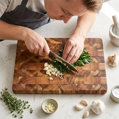 Personne coupant des légumes frais sur une planche à découper en bois pour préparer une salade