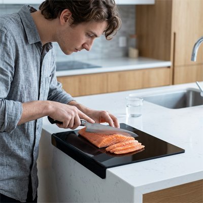personne utilisant une Planche a decouper sur un comptoir de cuisine 