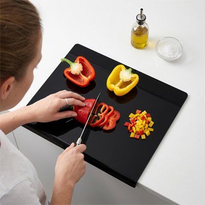 Planche a decouper de couleur noir entrain d'être utiliser pour découper des légumes