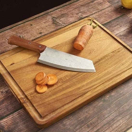 Planche à découper en bois avec un couteau et une carotte et tranchée dessus.