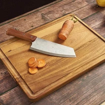 Planche à découper en bois avec un couteau et une carotte et tranchée dessus.
