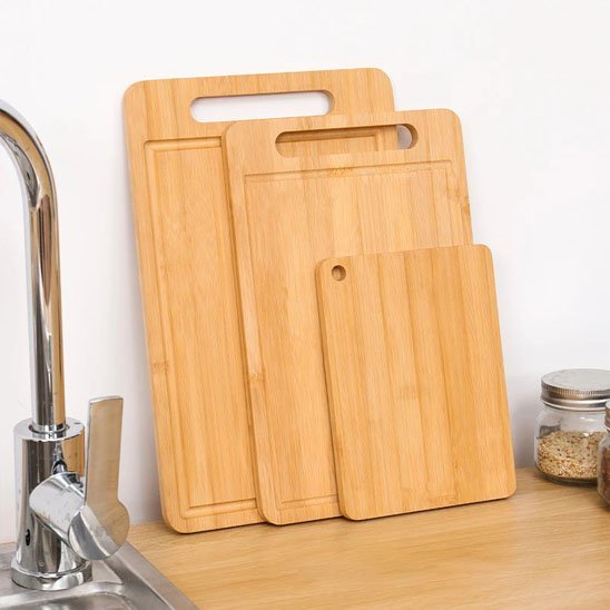 Planche à découper en bois posée sur un plan de travail avec légumes frais prêts à cuisiner.