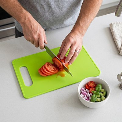 Planche à découper en plastique colorée, utilisée pour trancher des carottes.