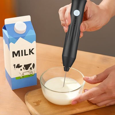 Préparation de mousse de lait avec mousseur électrique dans un pichet.