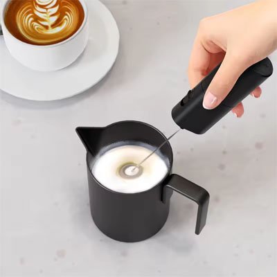 Préparation de mousse de lait avec un mousseur électrique en cuisine.