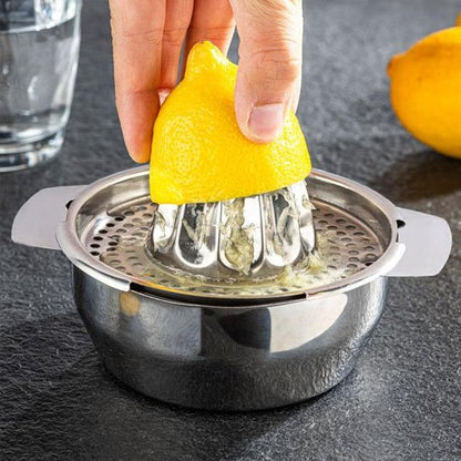 Presse agrumes manuel en inox utilisé pour presser une demi‑orange.