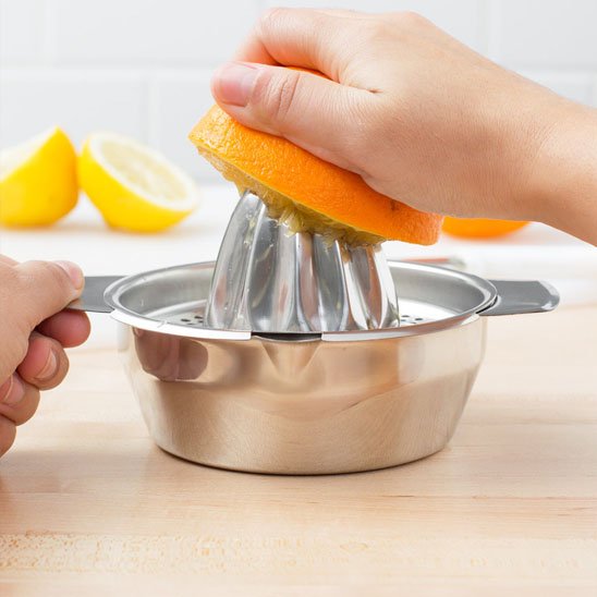 Presse agrumes métallique recueillant du jus frais sous un cône strié