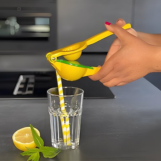 Presse‑agrume manuel jaune utilisé pour extraire du jus de citron frais dans un verre transparent.