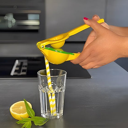 Presse‑agrume manuel jaune utilisé pour extraire du jus de citron frais dans un verre transparent.