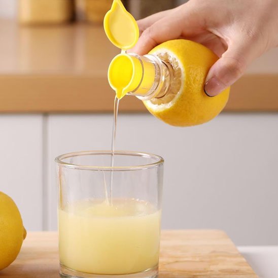 Presse‑agrume posé sur une table avec jus fraîchement servi.