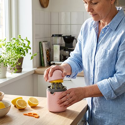 Presse‑agrumes coloré utilisé pour presser un citron dans une cuisine lumineuse.